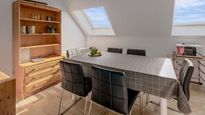 A dining area with a high ceiling, skylights, a wooden bookshelf, and a table with chairs. - 2 bedroom accommodation in Koksijde (Koksijde)