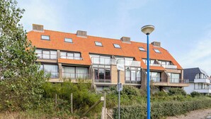 A residential building with a red-tiled roof, multiple windows, and a street lamp. - ZeeZonZand C-0206 + G* (Koksijde)