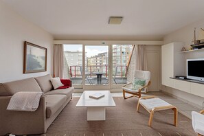 Una sala moderna con un sofá, una mesa de centro, una silla y un televisor.