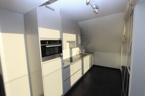Een koelkast, een microgolfoven, een oven, kookgerei, borden en bestek