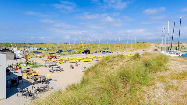 A beachside area with multiple sailboats, a sandy beach, and a small building with outdoor seating. - 1 bedroom accommodation in De Panne (De Panne)