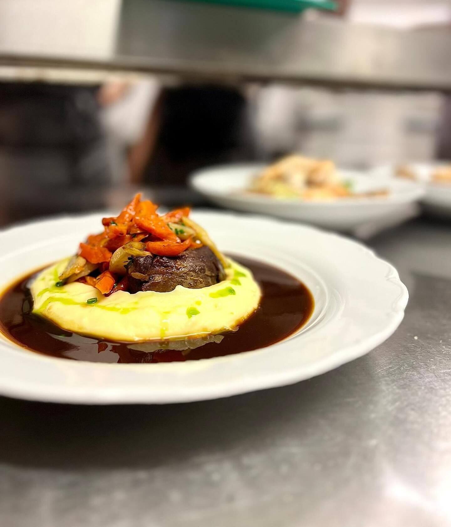 A plate of food with a mushroom and vegetables on a bed of mashed potatoes, served in a white bowl.