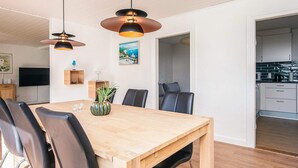 A modern dining area with a wooden table, black chairs, and pendant lighting. - 4 Star Holiday Home in Lokken (Logstor)