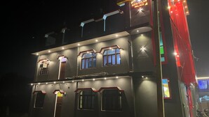 Un immeuble à plusieurs étages, doté d’une enseigne lumineuse, d’un balcon et d’une série de fenêtres.