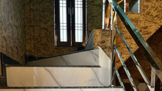 Un escalier avec des marches en marbre blanc et une rampe en métal.