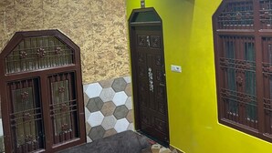 Une pièce avec un canapé, une porte portant un numéro, un mur orné d’un motif géométrique et un lustre.