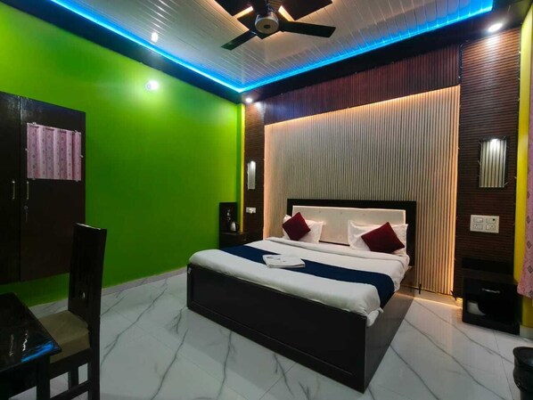 A modern hotel room with a bed, a ceiling fan, and a green wall.