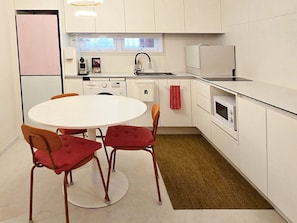 A modern kitchen with white cabinets, a round dining table, and two chairs.