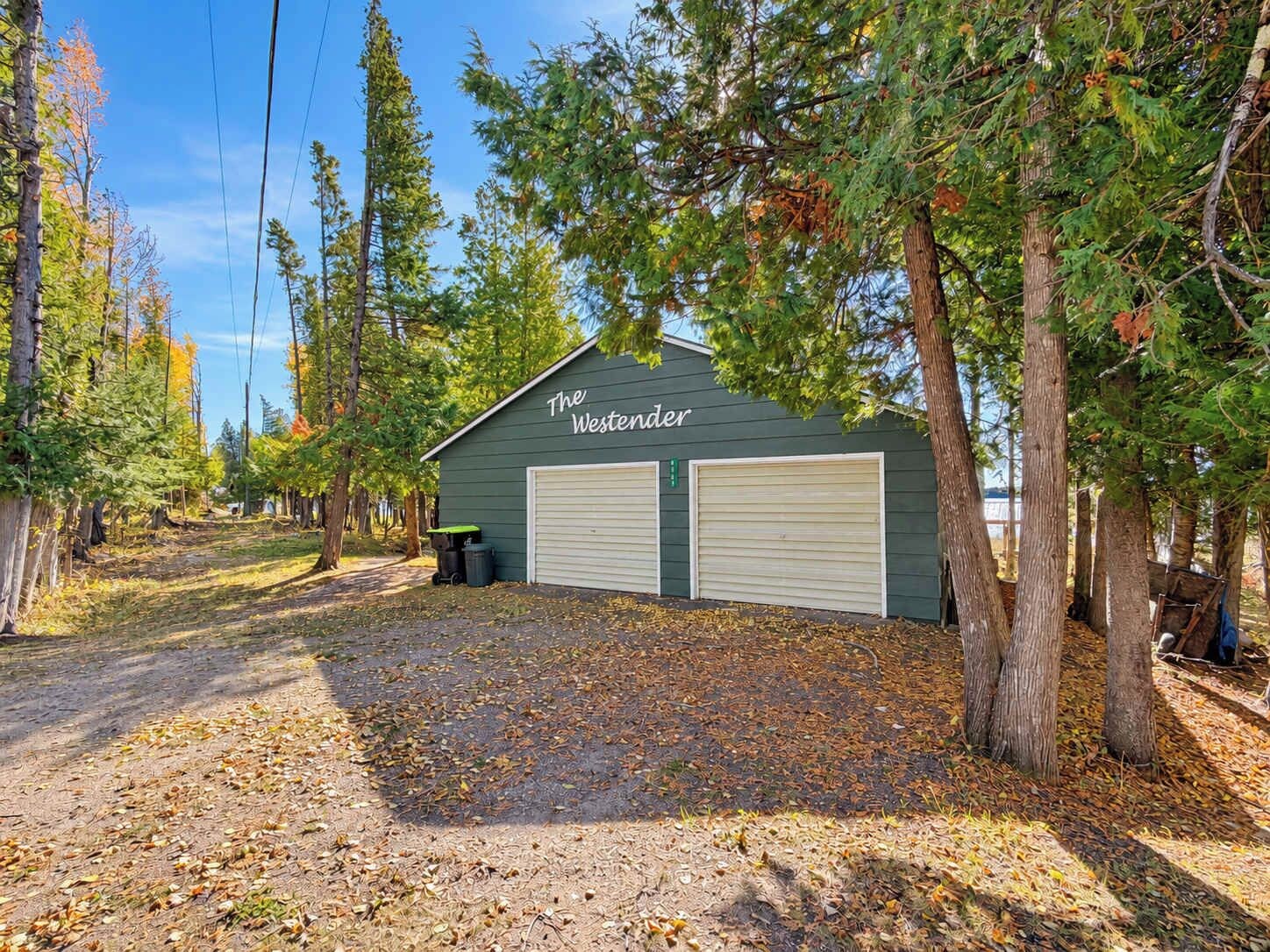 A building named 'The Westerner' with two garage doors, surrounded by trees and a gravel driveway.