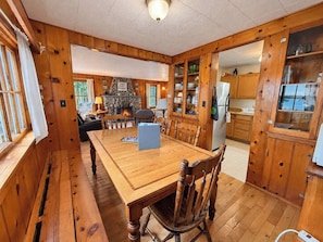 Un intérieur en bois comprenant une table à manger, des chaises, une cheminée et des meubles de cuisine.
