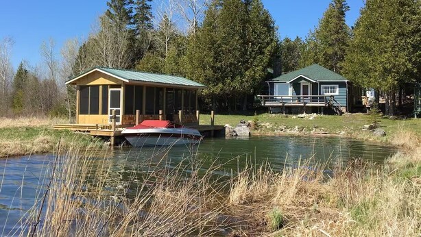 A cabin with a dock and a boat, surrounded by a forest and a pond. - The Westender Retreat | Amazing Lake Views & Waterfront Dock House (Hessel)