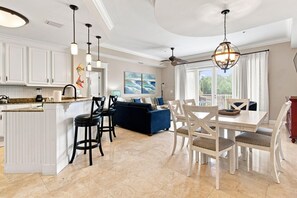 A modern kitchen with white cabinetry, a central island, and pendant lighting.