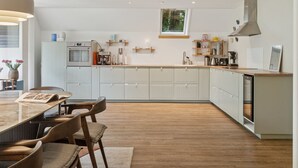 A modern kitchen with white cabinets, a wooden dining table, and a large window. - "Estefania" - 1km from the sea by Interhome (Vejby)
