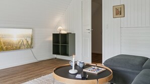 A cozy room with a round coffee table, a grey sofa, a bookshelf, and a painting on the wall. - "Estefania" - 1km from the sea by Interhome (Vejby)