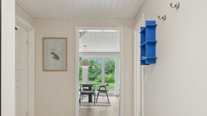 A hallway with a wooden floor, a framed chart on the wall, a dining area with chairs and a table, and a blue shelving unit. - "Estefania" - 1km from the sea by Interhome (Vejby)
