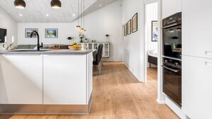 A modern kitchen with a central island, pendant lighting, and a built-in oven.
