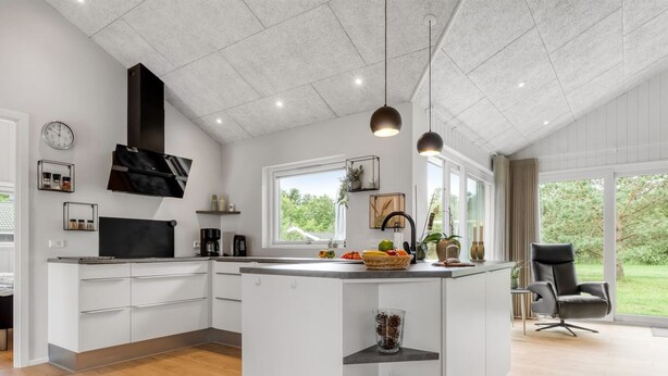 A modern kitchen with white cabinetry, a central island, and a large window offering a view of the outdoors.