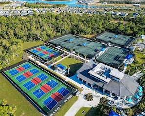 An aerial view of a resort with multiple tennis courts, a swimming pool, and a large landscaped area.