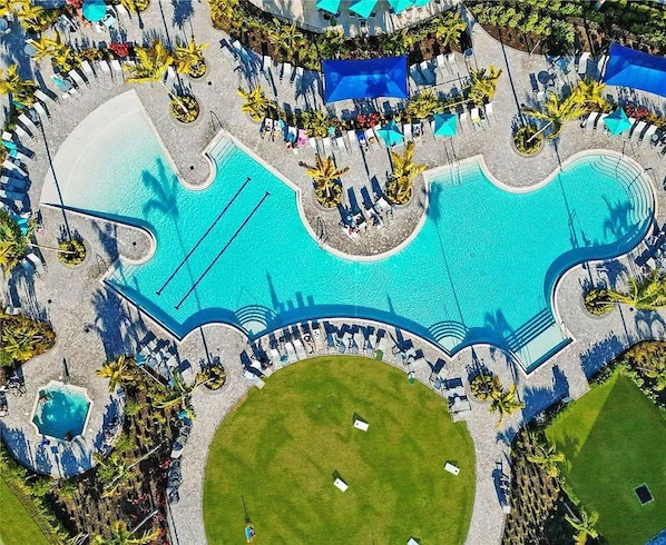 An aerial view of a resort with multiple swimming pools, lounge areas, and green spaces.