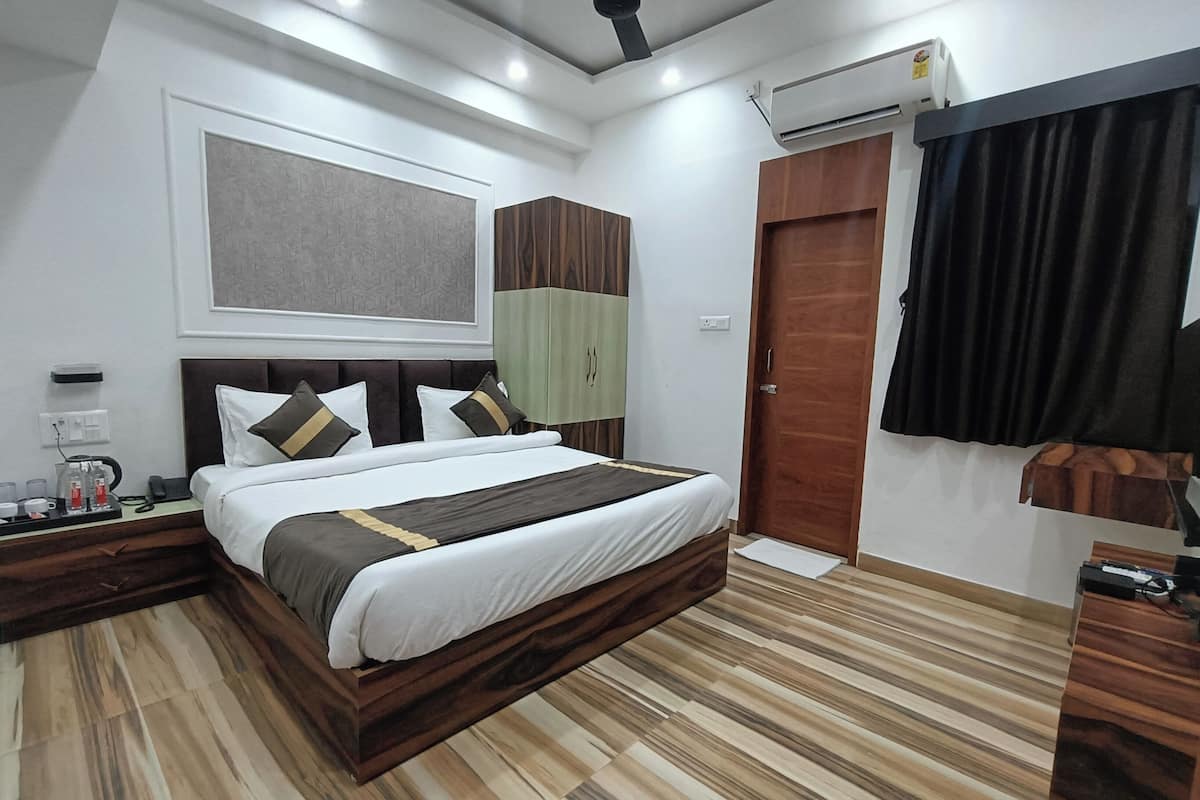 Una camera d'albergo moderna con un letto grande, pavimento in legno, ventilatore a soffitto, condizionatore d'aria e un armadio.