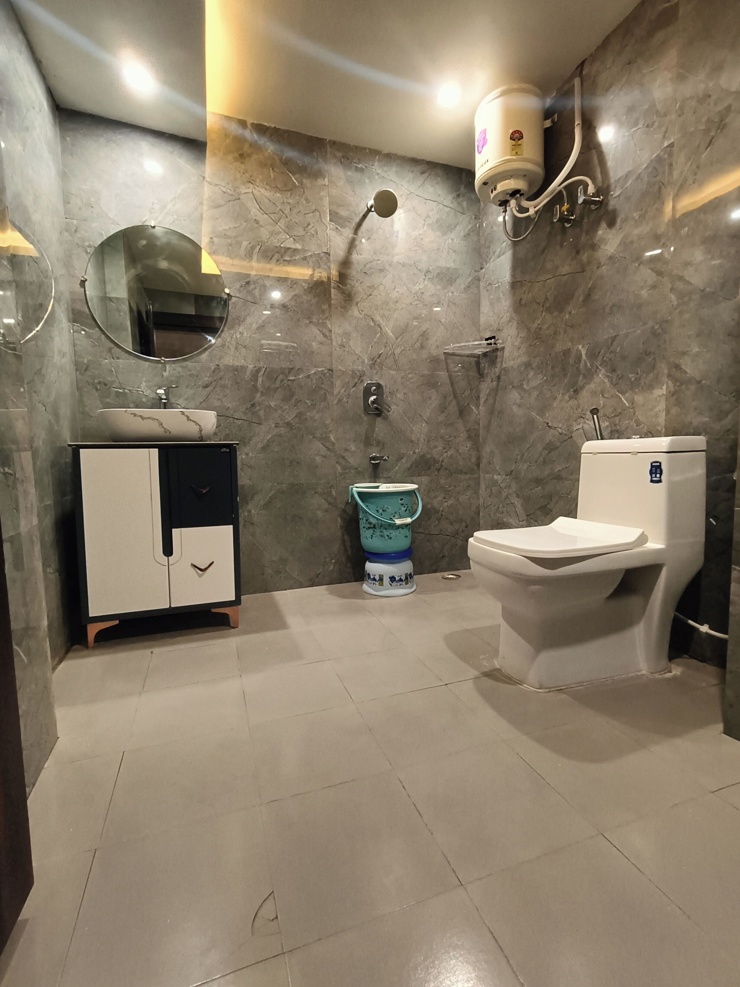 A bathroom with a marble wall, a sink, a toilet, and a mirror.