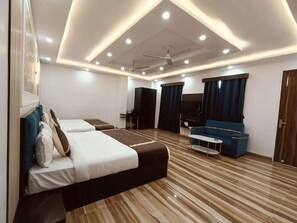 Une chambre d’hôtel moderne équipée de deux lits, d’un canapé, d’une télévision et d’un ventilateur de plafond.