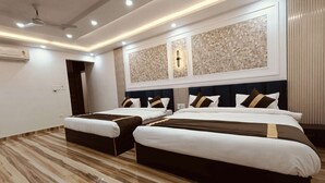 A modern hotel room with a large bed, two bedside tables, a ceiling fan, and a decorative wall panel. - CELESTIAL INN (Prayagraj)