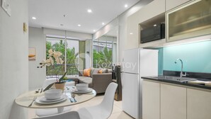 Een moderne keuken met een ingebouwde magnetron, een spoelbak en een eethoek met een ronde tafel en stoelen.
