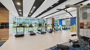 Een moderne sportschool met loopbanden, krachttoestellen en een groot raam met uitzicht op de omgeving.