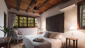 Un dormitorio acogedor con techo de madera, una cama con una bandeja de desayuno, una silla y una ventana con cortinas.