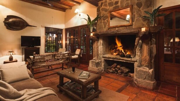 Una sala de estar acogedora con chimenea de piedra, muebles de madera y un televisor.