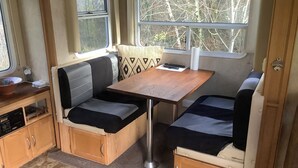 A compact RV interior with a kitchenette, a dining table, and seating area.