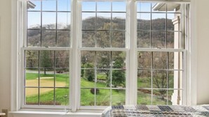 A room with a large window offering a view of a green landscape and hills. - Mountain View Fore You - Golf Front 2 BR, 2BA Condo (Maggie Valley)