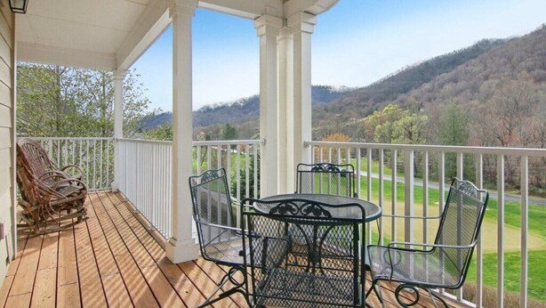 A covered porch with a wooden deck, metal chairs, and a table. - Mountain View Fore You - Golf Front 2 BR, 2BA Condo (Maggie Valley)