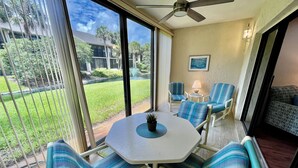 A sunlit room with a large window, a ceiling fan, and a table with chairs. - Best Address at the Beach, Gold-rated condo just a short walk to the beach! (Saint Augustine)