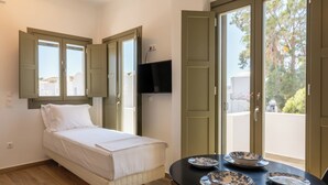 Una camera da letto con un letto, un tavolo con piatti e una TV appesa al muro.