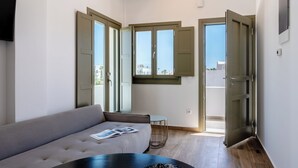 Un soggiorno moderno con un divano grigio, un tavolino rotondo e una TV fissata alla parete.