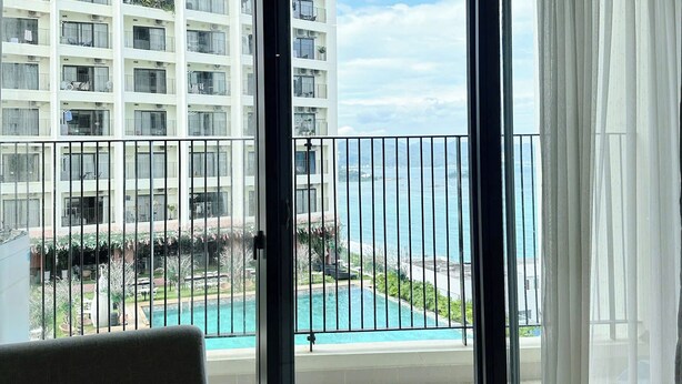 A balcony with a view of a swimming pool and a high-rise building. - Gold Coast Mall Nha Trang - LT housing (Nha Trang)