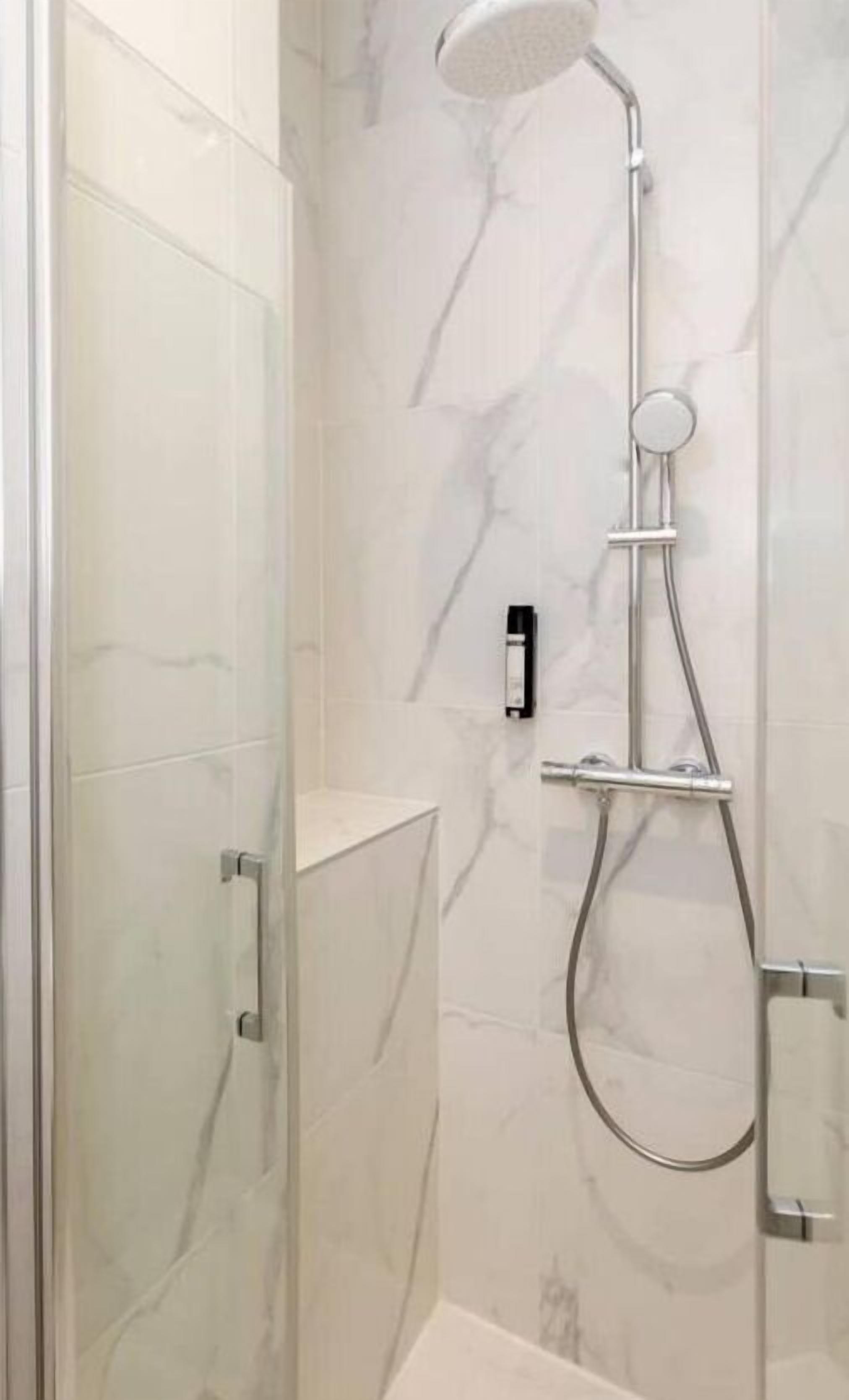A modern shower with a handheld showerhead and a wall-mounted control.