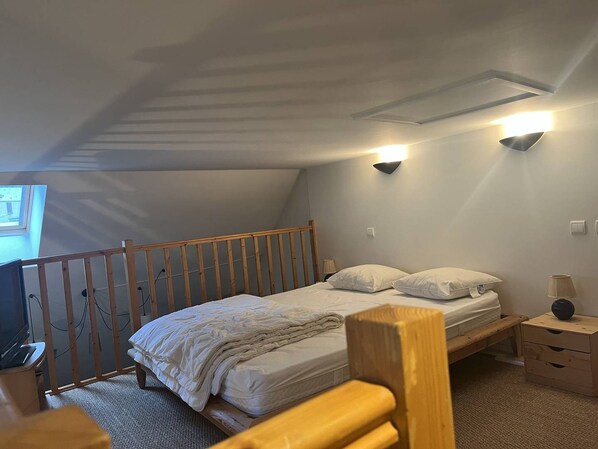 A bedroom with a single bed, a wooden headboard, a nightstand, a lamp, and a wall-mounted light fixture.