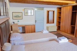 Une chambre avec deux lits, une armoire en bois, un bureau et un miroir.