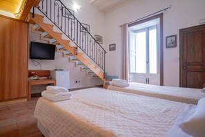 A hotel room with a wooden staircase, a television, a desk with a computer, two beds with towels, and a large window. - Himera Domus 2 - Comfort and relaxation in the heart of Termini Imerese (Termini Imerese)