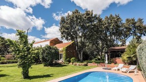 A swimming pool with a clear blue water, surrounded by a well-maintained lawn and trees.