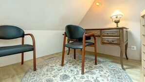 Una habitació amb dues cadires, un escriptori, una làmpada i una catifa amb dibuixos.