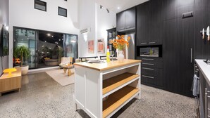 Una cocina moderna con armarios oscuros, una isla central y un ventanal grande.