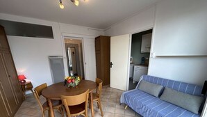 Ein gemütlicher Wohnbereich mit Esstisch, Stühlen, einer Couch und einer Küchenzeile.