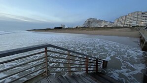 Ein Strand mit einer Holzpromenade, die zu einem Sandufer führt.