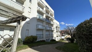 Ein mehrgeschossiges Wohnhaus mit Balkonen, einem gepflasterten Weg und einem kleinen Garten.