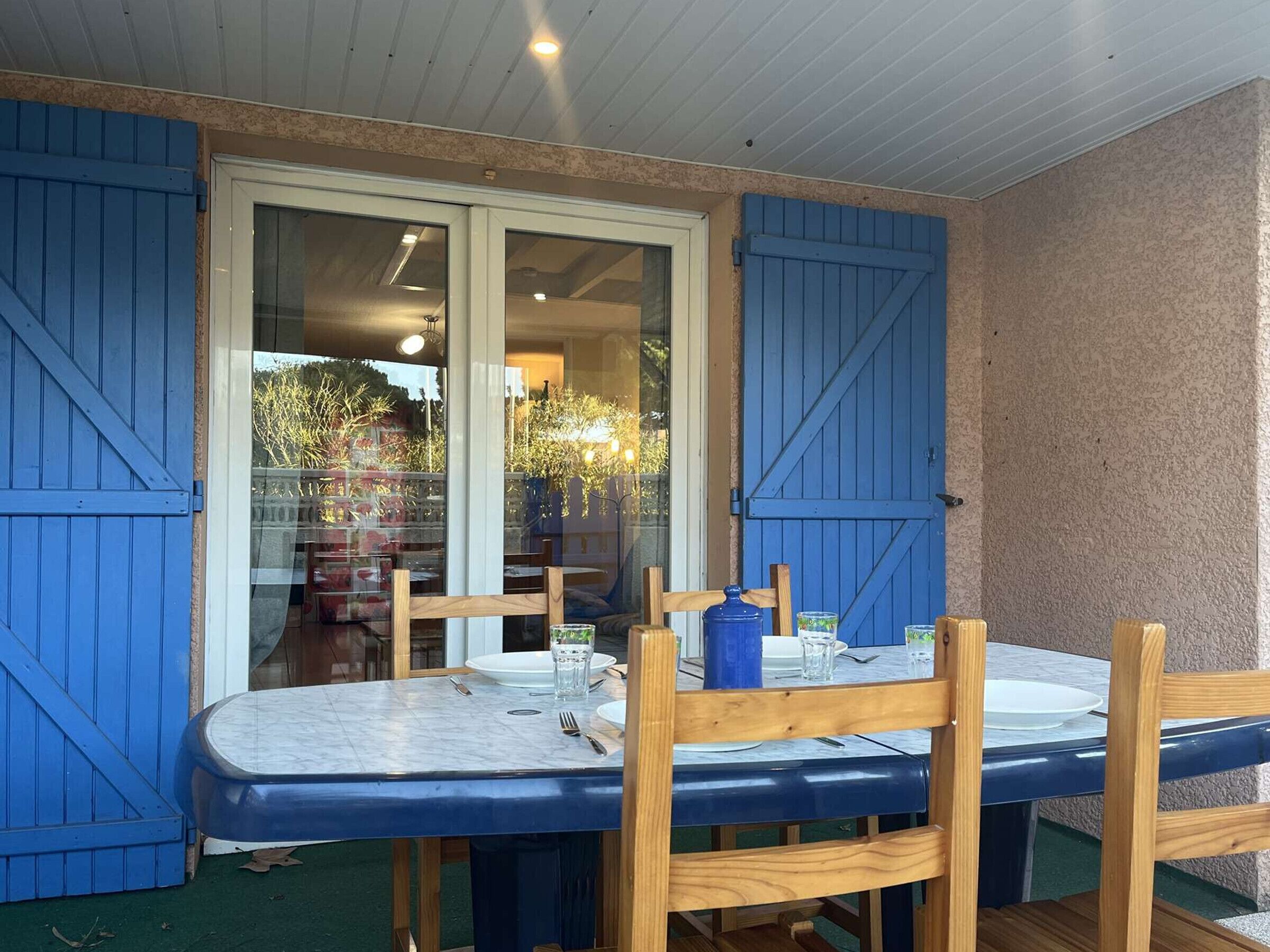 Ein Essbereich mit Tisch und Stühlen, eine Glastür zu einem Außenbereich und ein blauer Türrahmen.