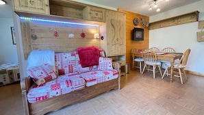 A cozy room with a wooden sofa, a dining table with chairs, and a fireplace. - 2-bedroom apartment at the ski slopes with indoor pool (Flumet)